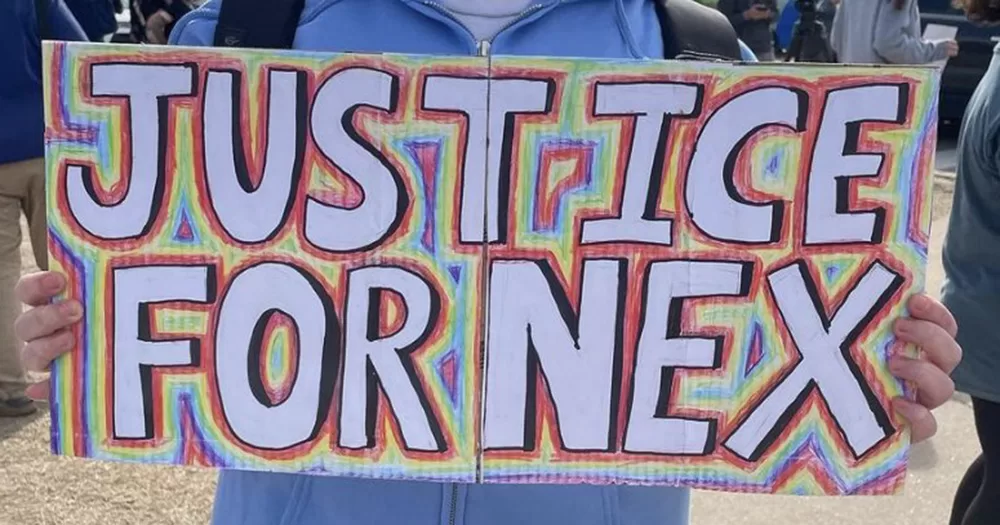 This article is about a federal investigation being launched into the Oklahoma school district following the death of Nex Benedict. The image shows a colourful cardboard sign reading, "Justice for Nex".