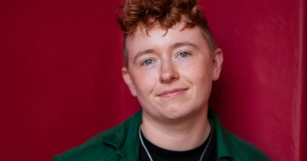 This article is about a yes no vote in the upcoming referendums. In the photo, activist Ruadhán Ó Críodáin smiling at the camera on a red background.