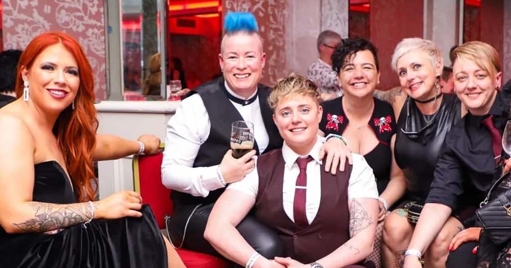 Photo of queer women in suits sitting together at the Cork women's weekend