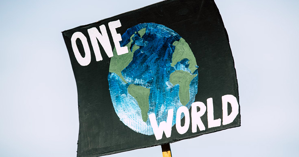Picture of an environment protest sign with the earth and the words "One World" for Earth Day.