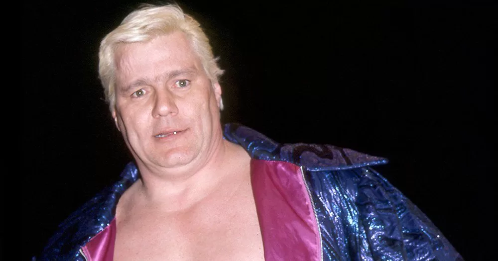 An image of Pat Patterson. He is photographed from the chest up, with his bare chest on show. He also has a jacket draped over his shoulders.