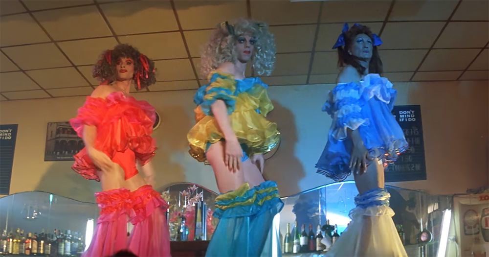 The picture shows the three main characters from The Adventures of Priscilla, Queen of the Desert dancing on a table.