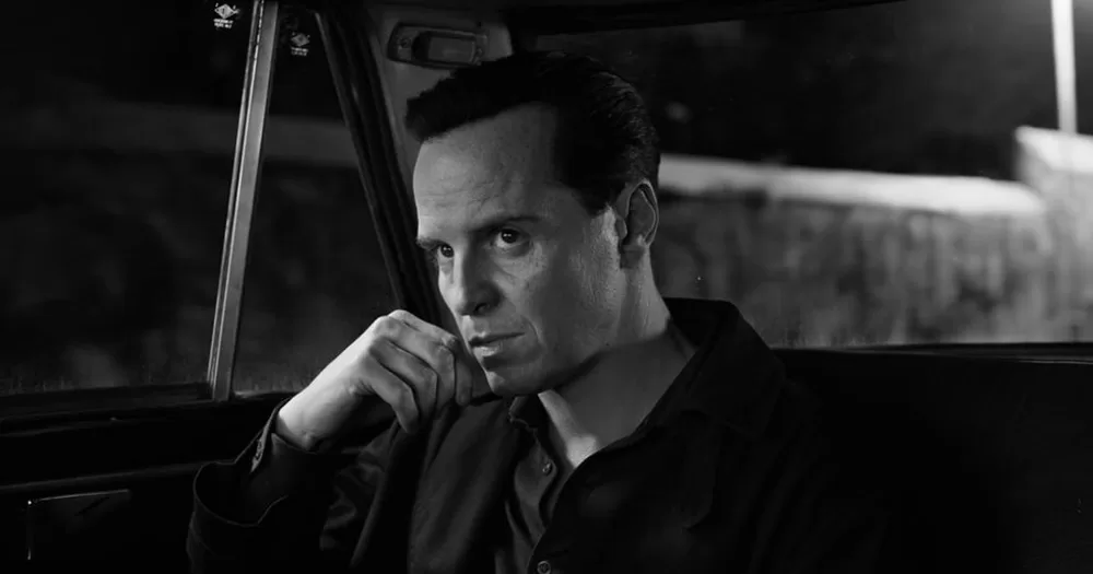 A still of Andrew Scott as Ripley. The image is in black and white, and shows Scott sitting in the back of a car.