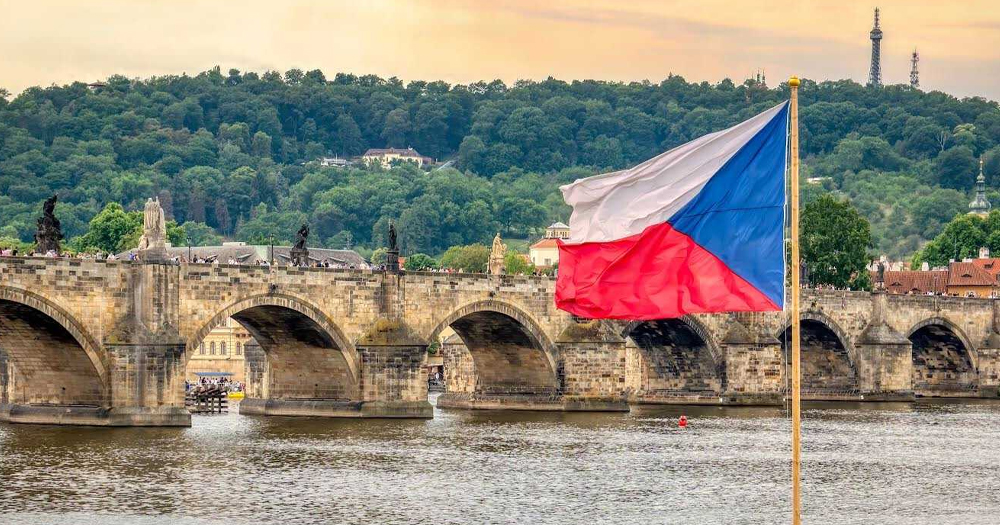 A photo of the Czech Republic flag overlooking a scenic river.