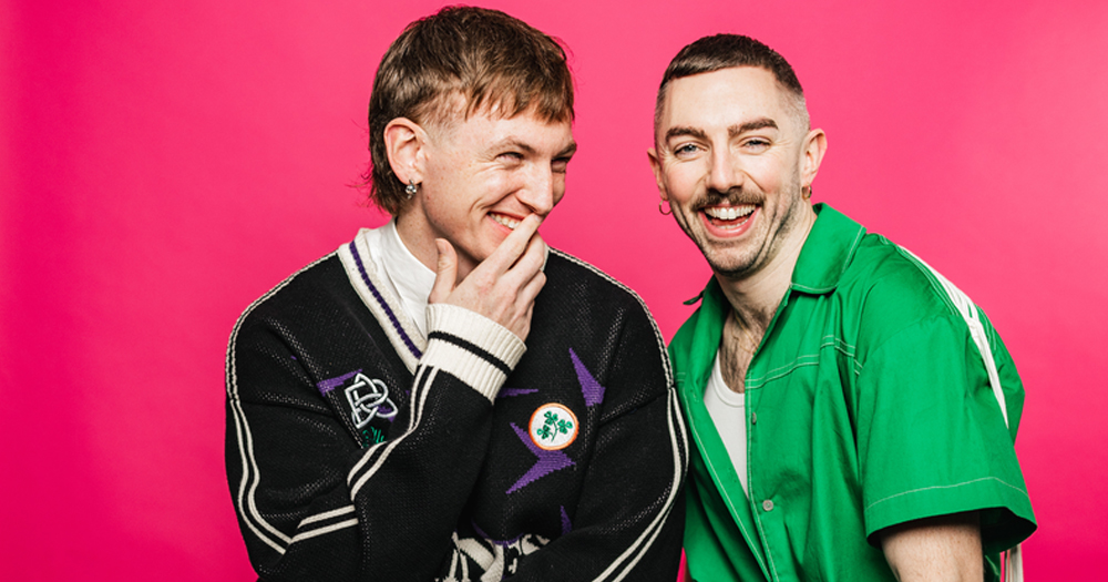 The I'm Grand Mam duo, who are getting ready for the live tour, laughing while posing for a photo in front of a bright pink background.