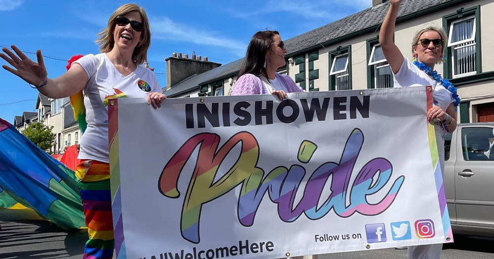 People marching in the Inishowen Pride Parade carrying a banner printed with the event's name.