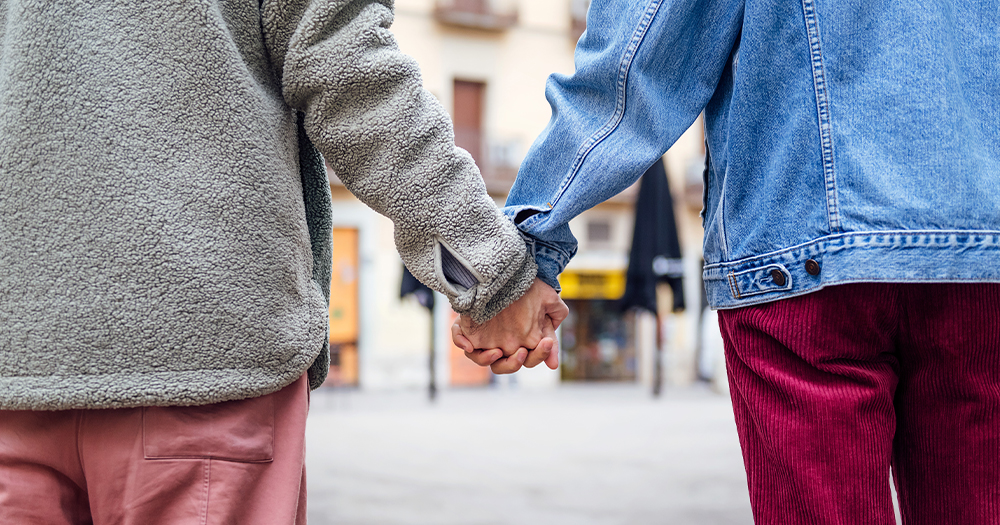 This article is about LGBTQ+ people in Ireland saying they fear being assaulted in certain places. In the photo, two people holding hands and facing away from the camera.