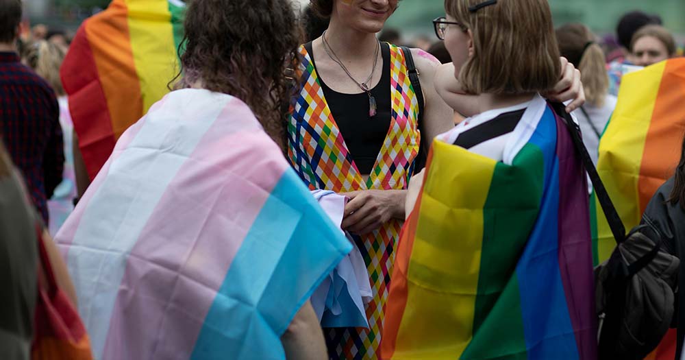Photo of three people wearing Pride flags representing Longford Pride.