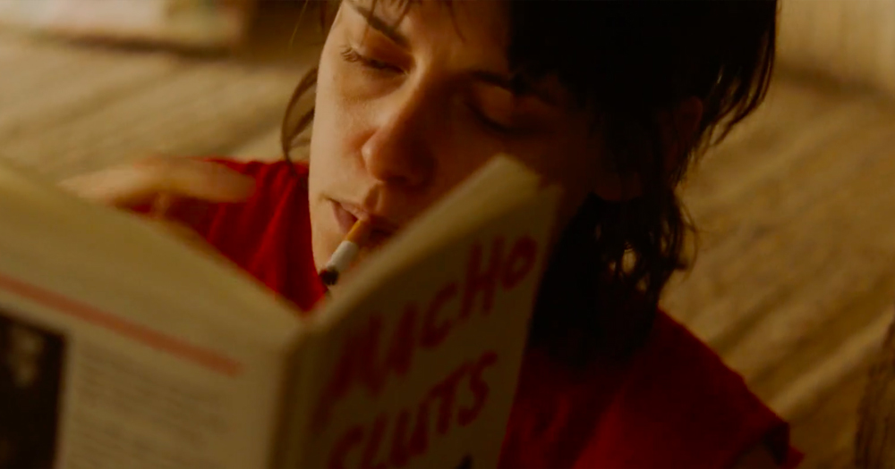 Kirsten Stewart reading the book Macho Slut and smoking in a scene of the film Love Lies Bleeding.