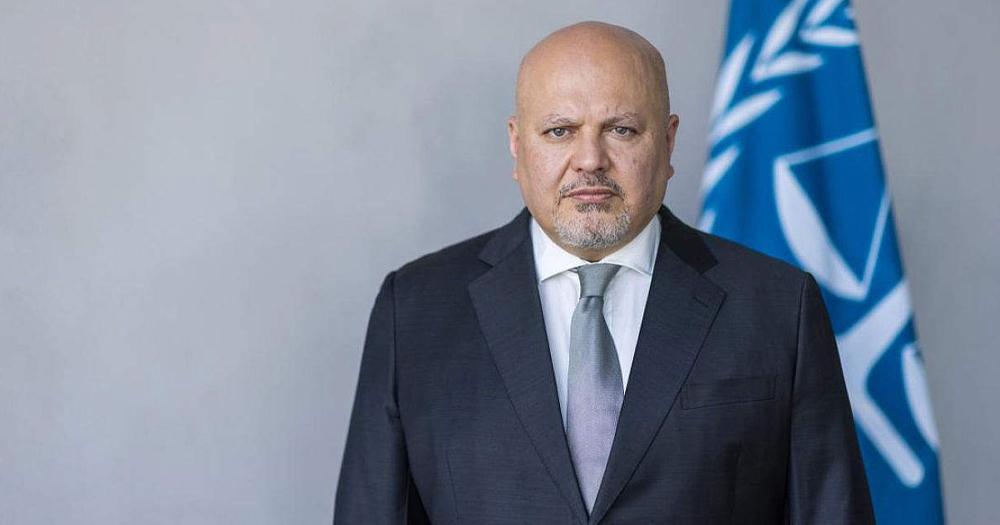 ICC chief prosecutor Karim Khan, who announced that he's seeking arrest warrants for Netanyahu and others, with the man facing the camera and a blue flag in the background.