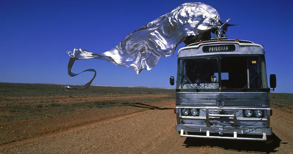 The bus of the movie Priscilla, Queen of the Desert driving in a road in the middle of the desert.