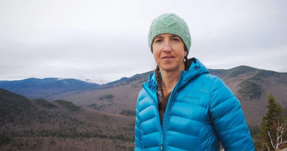 A photograph of Adirondacks forest ranger and trans trailblazer Robbi Mecus against a mountain background.