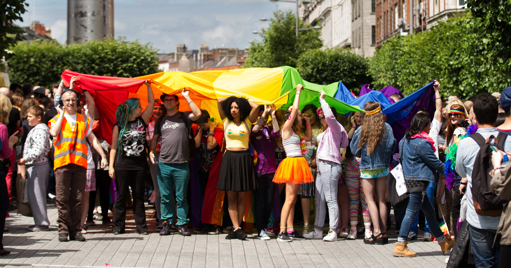 This article is about LGBTQ+ safe spaces. In the photo, a group of people holding up a massive Pride flag during Dublin Pride.