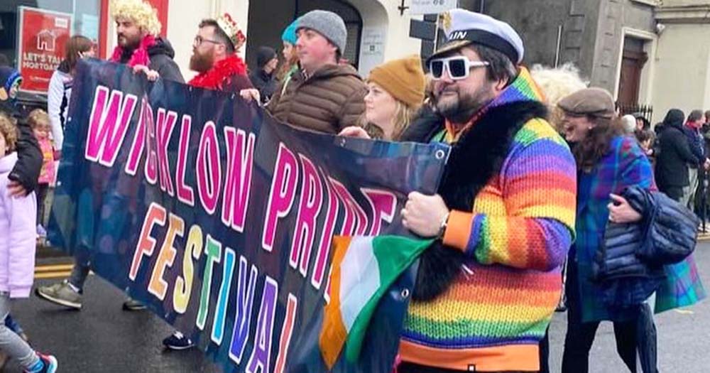 Photo of people wearing rainbow colours carrying a Wicklow Pride festival banner.