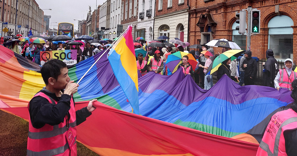 Image of a large rainbow flag being carried through the Dublin Pride Parade.