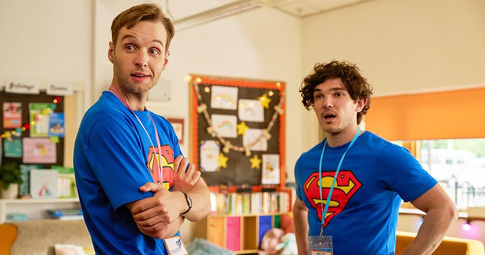 Screenshot from BBC drama Lost Boys and Faeries, with actors Fra Fee and Sion Daniel Young wearing matching Superman t-shirt with a school setting in the background.