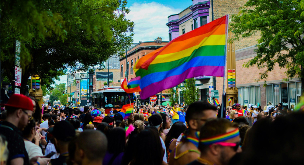 Crowd of people in a Pride parade, flying flags.