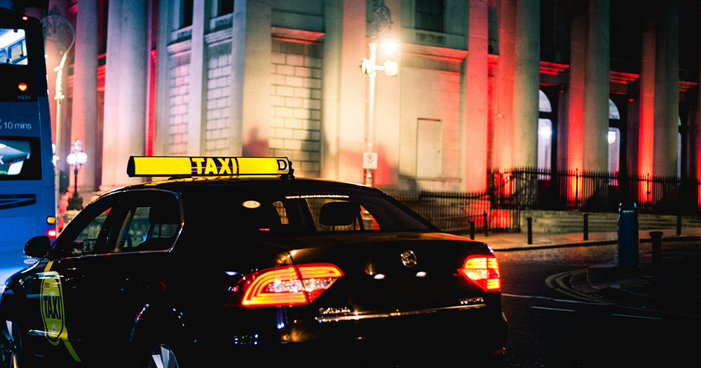 This article is about taxi shortages in Dublin. The image shows a taxi driving late at night.