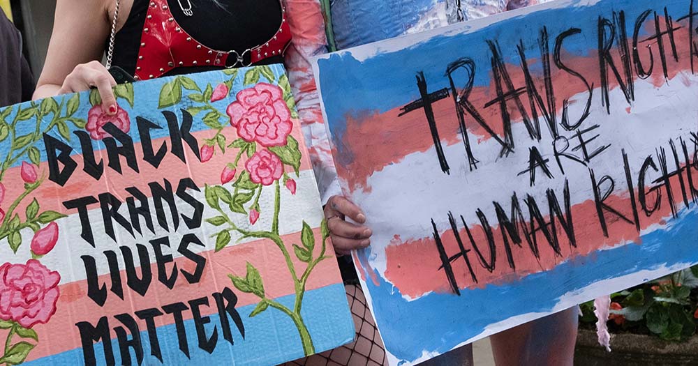 Two trans flag signs that say "Black Trans Lives Matter" and "Trans Rights are Human Rights" marking San Francisco becoming a sanctuary city.