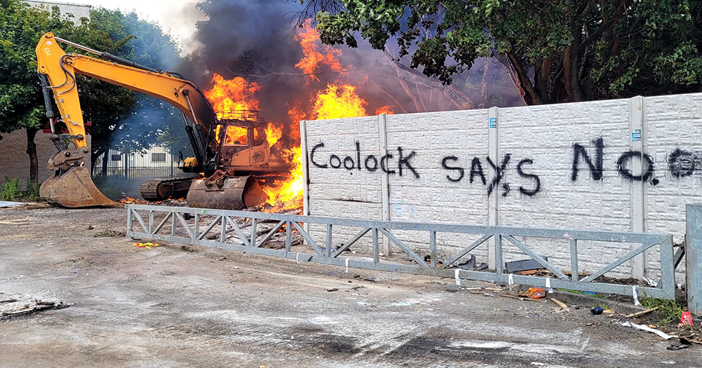 An image taken from the July 15 anti-immigration riots in Coolock, North Dublin showing a burning excavator and a brick wall with graffitti reading: "Coolock Says No".