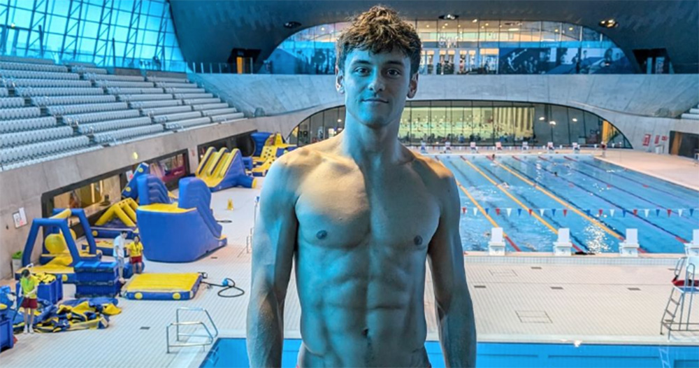 Openly gay Olympic diver Tom Daley, who tested out the 'anti-sex' beds in Paris. He is photographed shirtless from the waist up with a pool visible in the background.