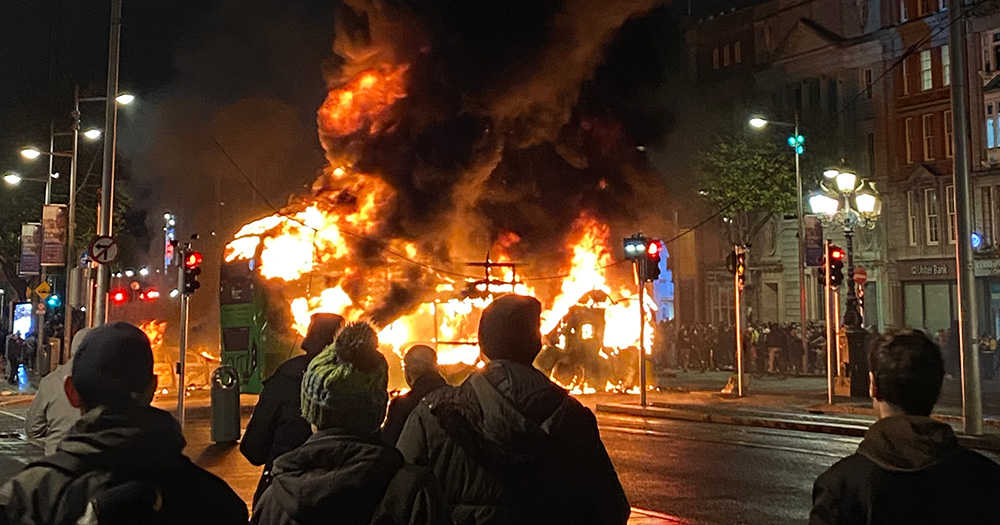 An image from the Dublin Riots, which have led to 49 people being arrested. The image shows a bus on fire, as a group of people look on.