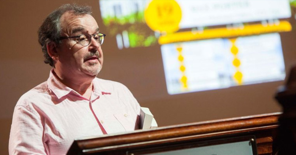 A photo of the late Dr Éibhear Walshe, Director of Creative Writing at University College Cork, standing at a UCC podium.