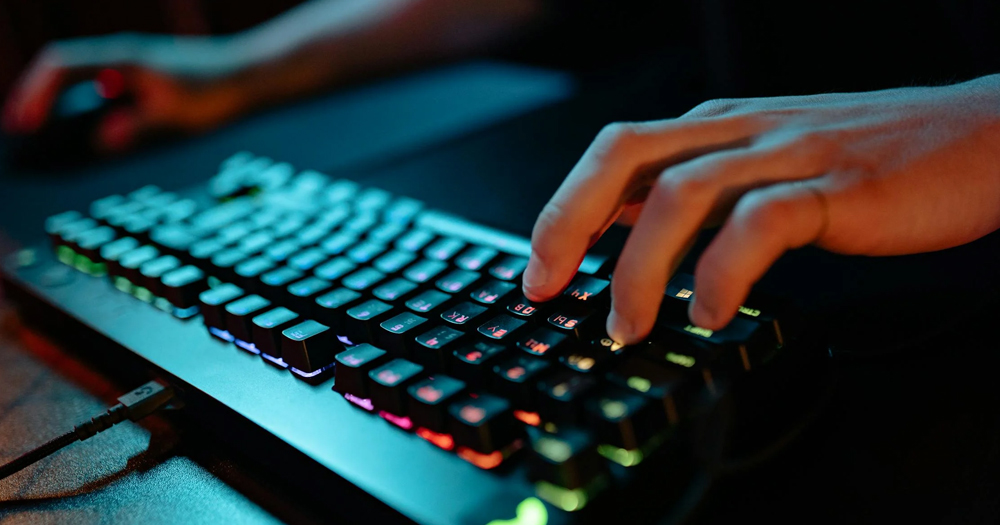 This article is about hackers stealing data from Project 2025. The image shows the hand of a person typing on a keyboard in a dark room.