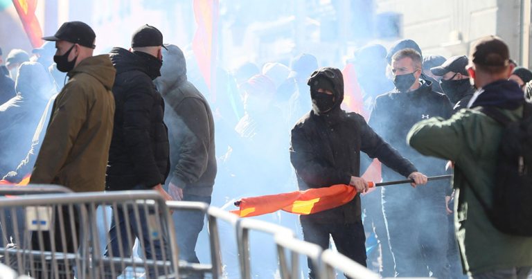 This article is about a former Ku Klux Klan senior member meeting with Irish far-right groups. Photo of Irish far-right protestors on the streets wearing masks.