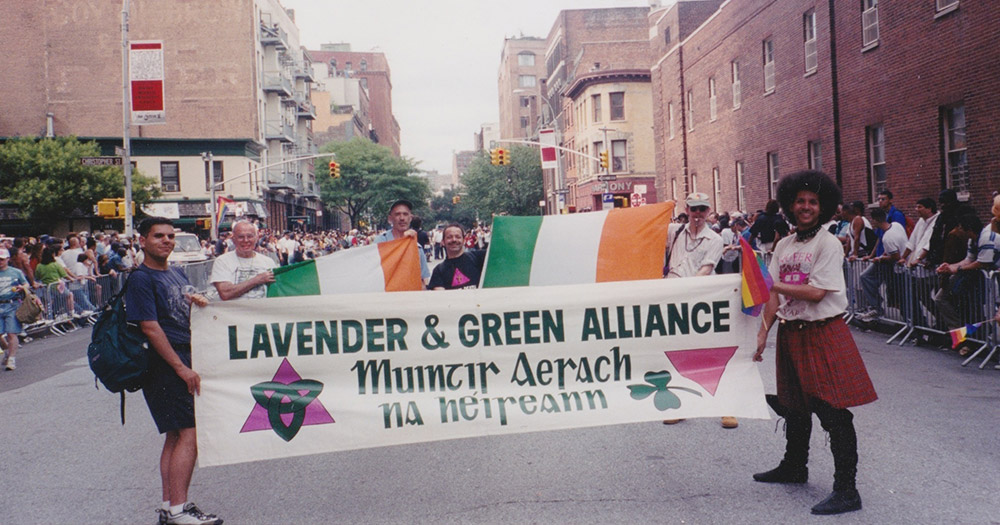 A photo of the Lavender and Green Alliance holding a banner and Irish flags in a parade.