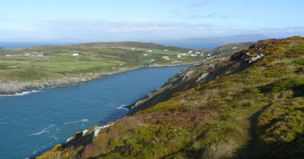 Image of Cape Clear where the LGBTQ+ Gaeltacht is taking place. It shows the sea and mountains and fields.