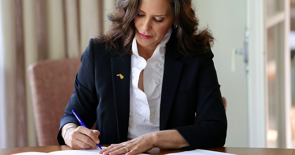 Michigan Governor Gretchen Whitmer, who signed the state's bill banning the gay panic defence, signs a piece of paper at her desk.