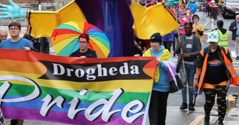 Photo of Drogheda Pride, which this year received online abuse prior to the event. In the image, people are marching carrying rainbow flags and a banner reading 'Drogheda Pride'.