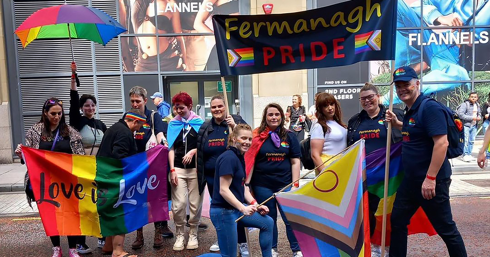 Organisers of Fermanagh Pride posing for a photo with rainbow flags and a banner that reads "Fermanagh Pride".