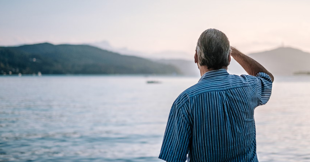 This article is about growing old as a gay man. In the photo, a man facing away from the camera and towards the sea.