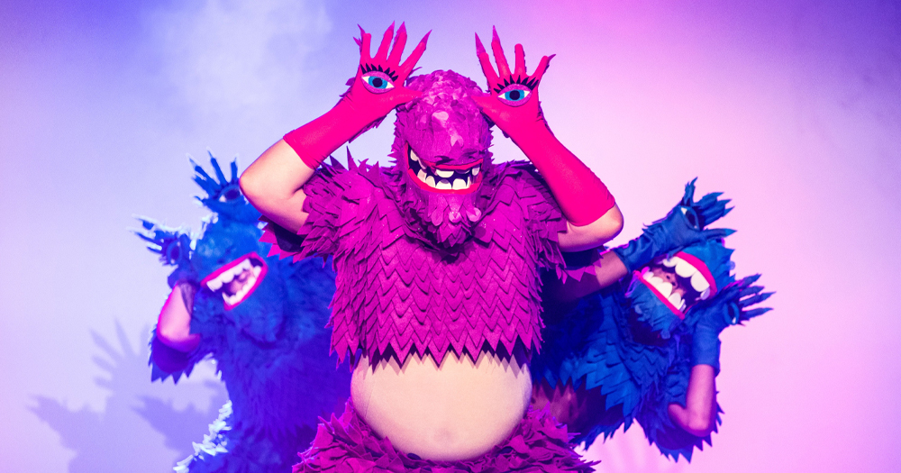 Photo of the MESSY FRIENDS show, showing performers in pink and blue costumes and masks doing a choreography.