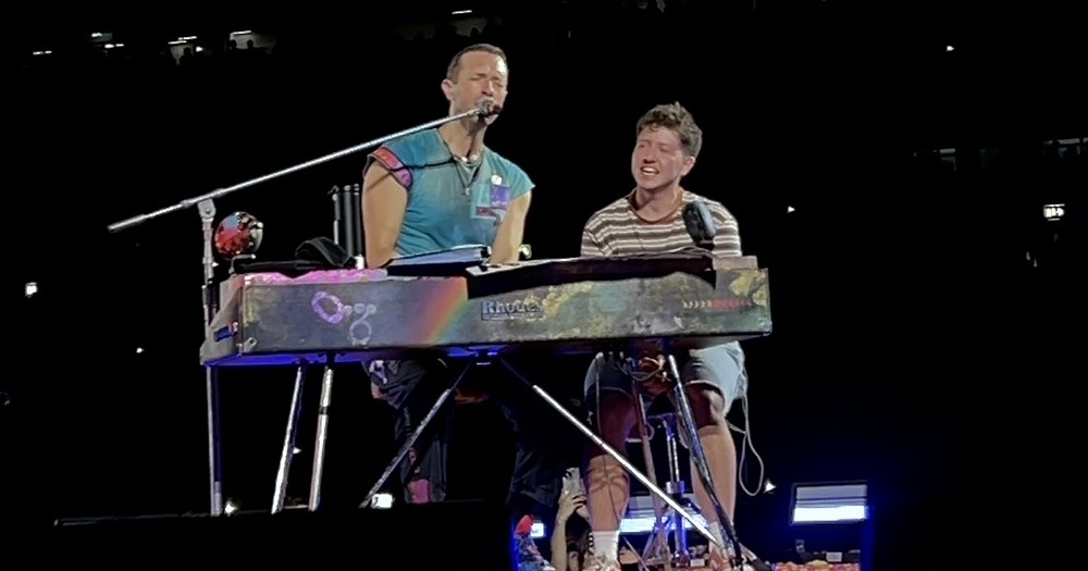 Coldplay frontman Chris Martin with a trans fan on stage singing while playing during a concert in Dublin.