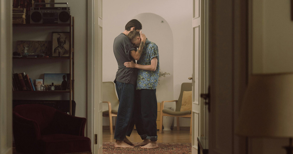 This article is about a new report examining intimate partner violence among gay and bisexual men in Cork. The image shows two men holding each other in a hallway.