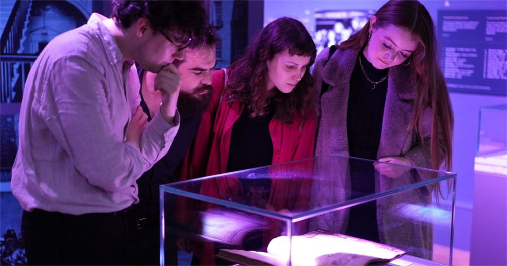 Four people looking at an exhibition item in the Museum of Literature Ireland.