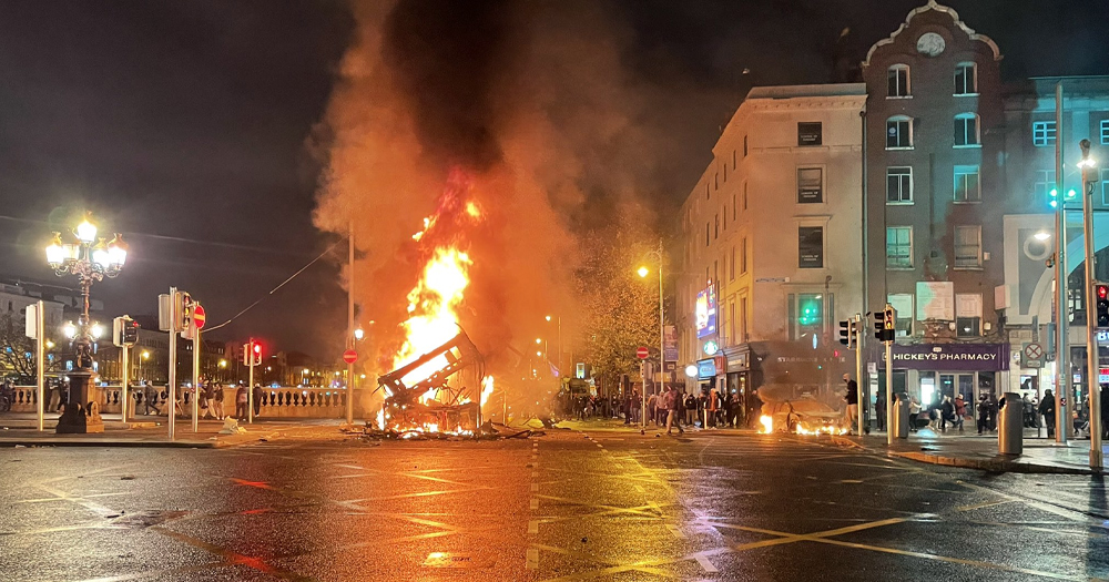 Photo of Dublin Riots, with a woman being recently arrested in connection, showing a fire on O'Connell Bridge.