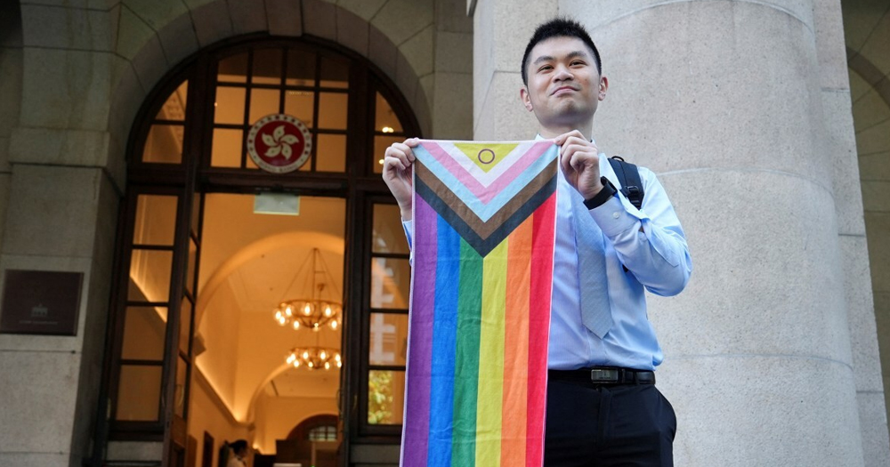 This article is about a Hong Kong court ruling on same-sex couples' rights. In the photo, one of the plaintiffs in the case posing in front of the court with an Pride flag.