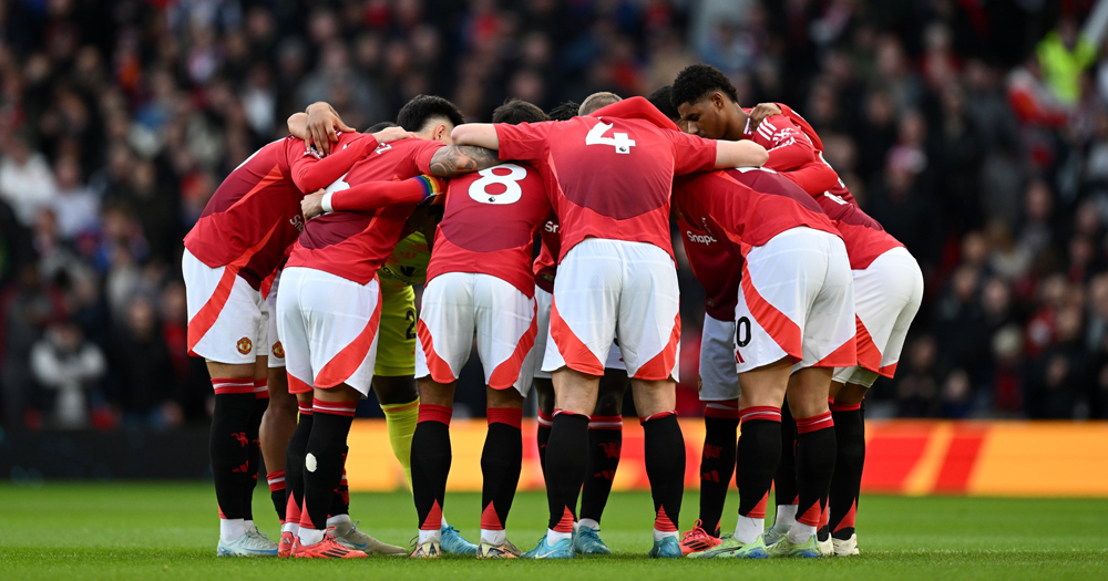 Manchester United team in the pitch, holding each other in a circle.