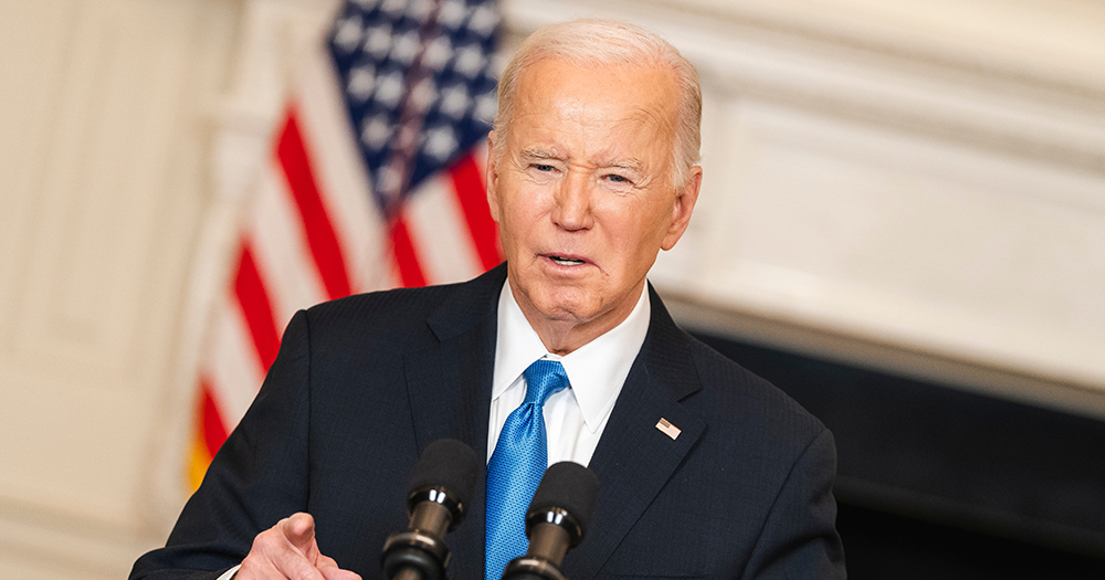 Photo of Joe Biden, whose administration expanded Title IX to increase protections for LGBTQ+ students, speaking into a microphone with a US flag visible in the background.