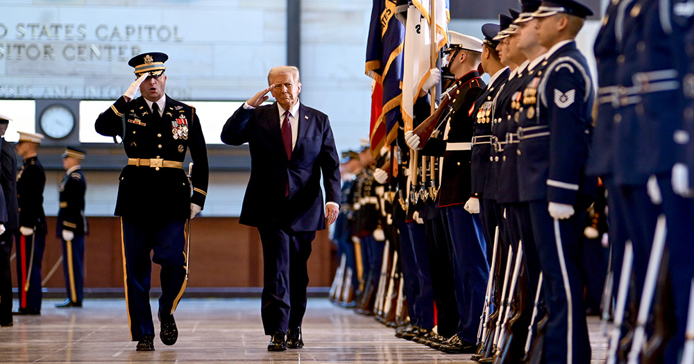 Image of US President Donald Trump saluting a row of military service members.