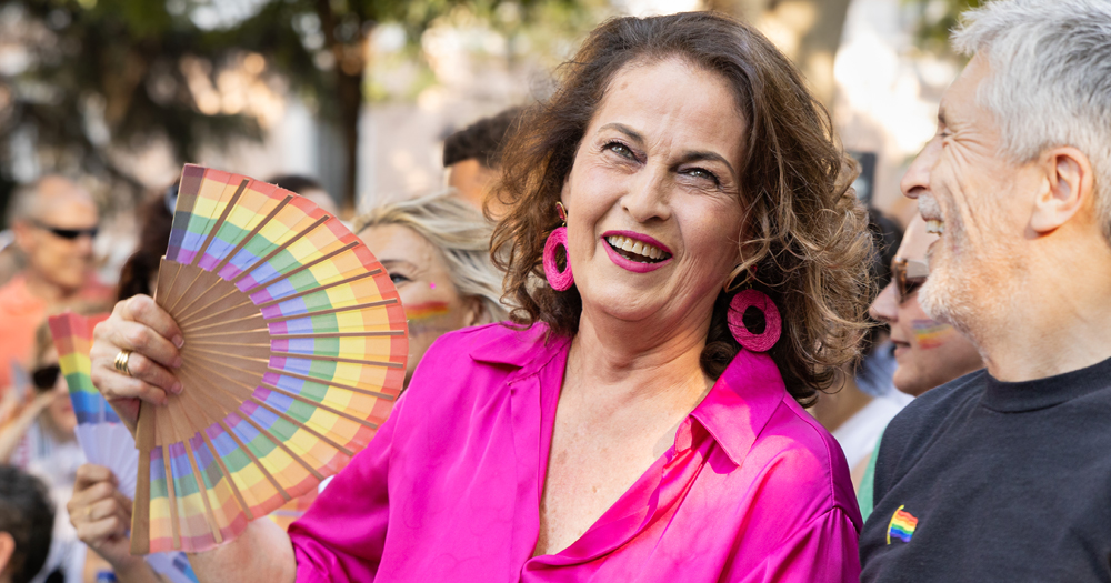 Photo of Carla Antonelli, Spain's first trans senator, participating in a Pride Parade, holding a rainbow fan.