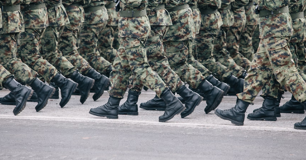 This article is about a judge blocking Trump's trans military ban. In the photo, the legs of several soldiers marching together wearing mimetic uniforms.