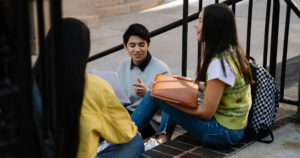 This article is about an LGBTQ+ mental health training. In the photo, young people chatting on the stairs.
