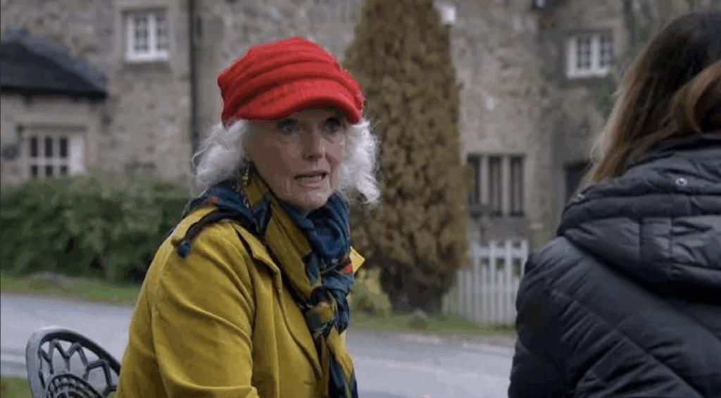 Mary is seen wearing a yellow coat and red hat while standing outside