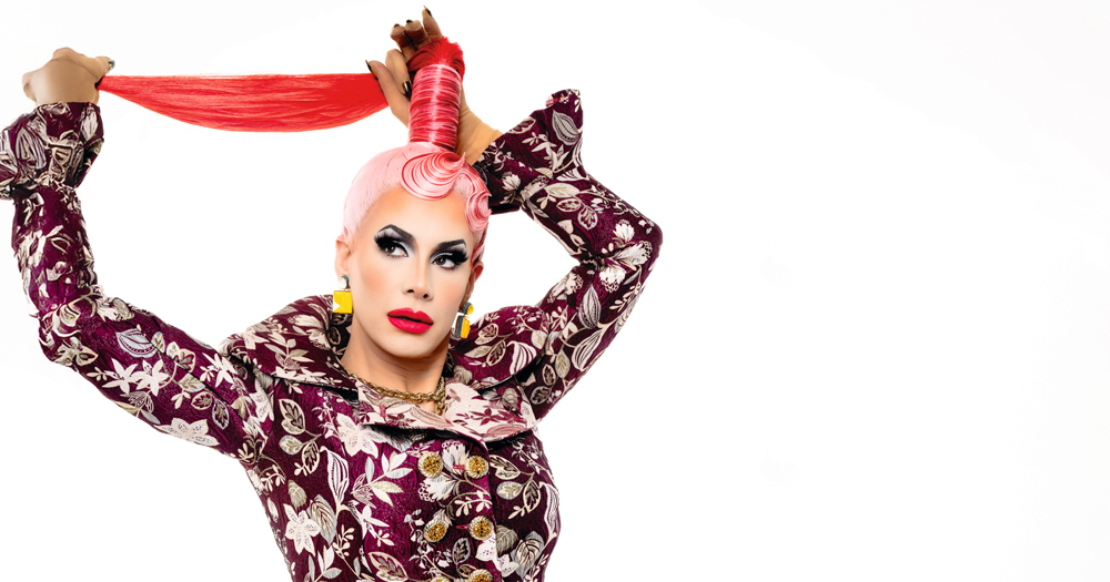 Drag performer Divina De Campo posing by holding her hair in a high ponytail.