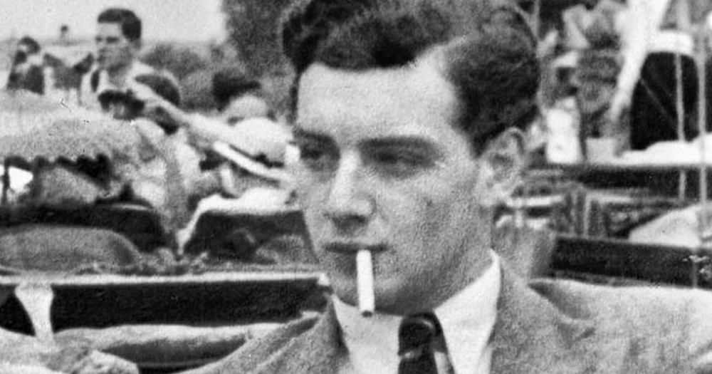 This article is about gay spies. The image is a black and white photo of a man smoking a cigarette.